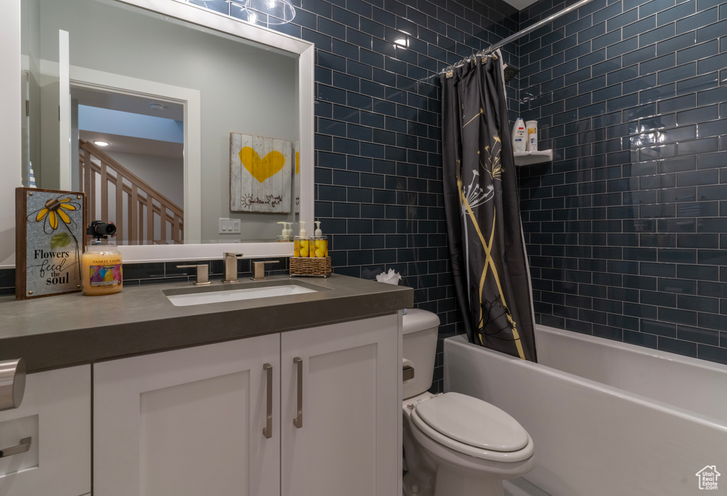 Full bathroom with shower / tub combo with curtain, vanity, toilet, and tile walls