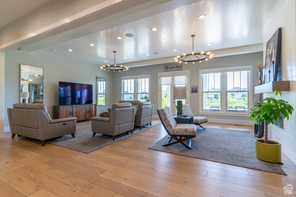 Living room with light hardwood / wood-style floors and a notable chandelier