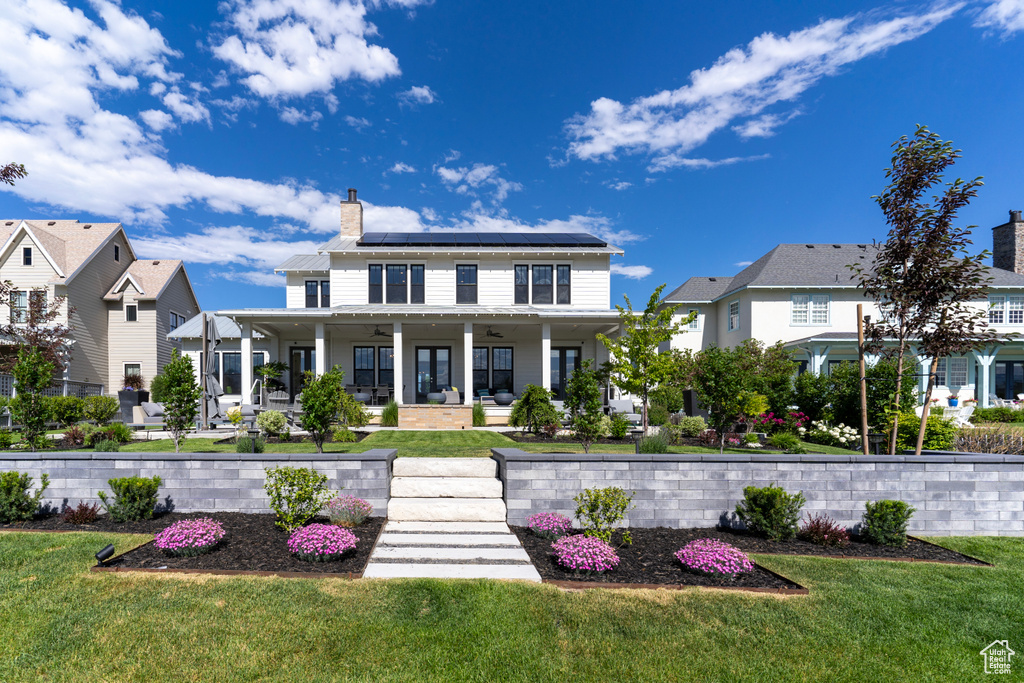 View of front of house with ceiling fan, a front lawn, covered porch, and solar panels