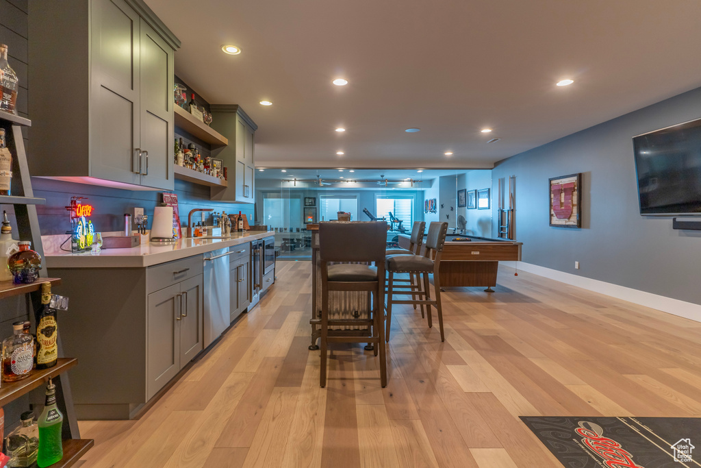 Kitchen featuring decorative backsplash, stainless steel dishwasher, a breakfast bar, and light wood-type flooring