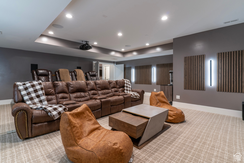Cinema room with a raised ceiling and light colored carpet