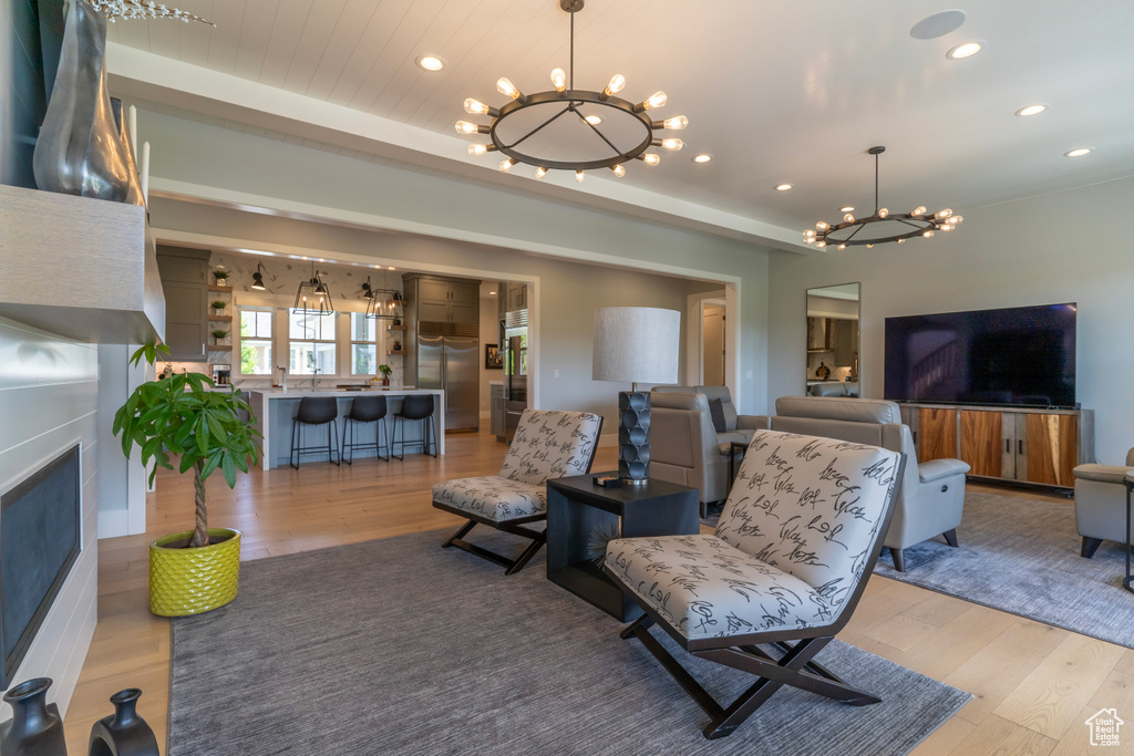 Living room with a fireplace, a chandelier, and light wood-type flooring