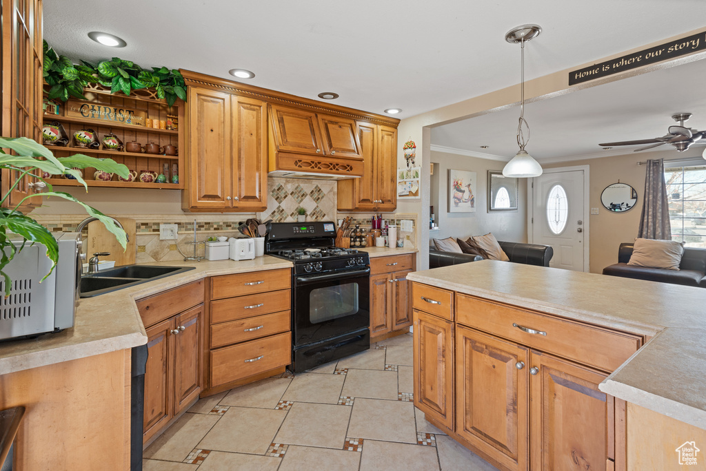 Kitchen featuring tasteful backsplash, light countertops, open floor plan, black range with gas cooktop, and a sink