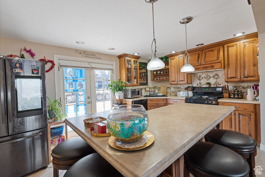 Kitchen with black appliances, backsplash, a sink, and brown cabinets