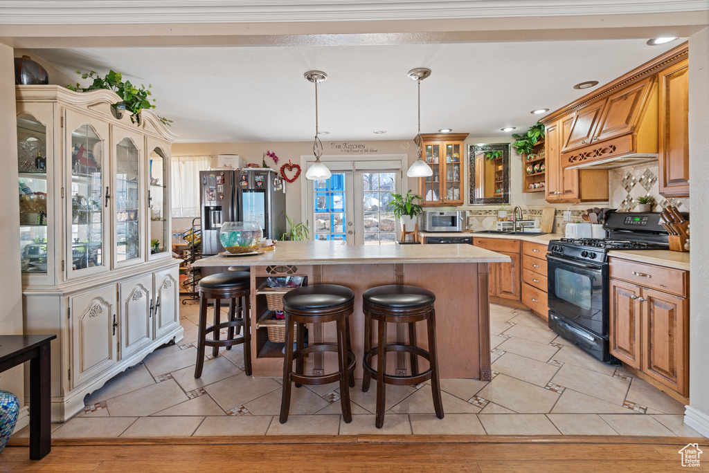 Kitchen with a center island, stainless steel appliances, tasteful backsplash, light countertops, and a kitchen bar