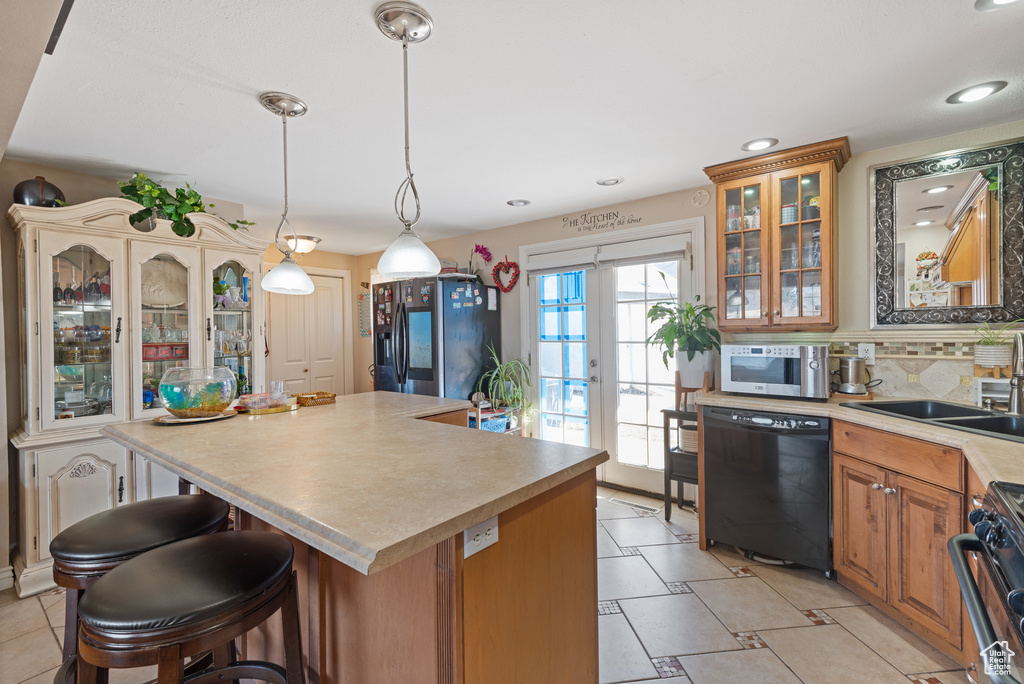 Kitchen featuring glass insert cabinets, a sink, stainless steel appliances, light countertops, and backsplash