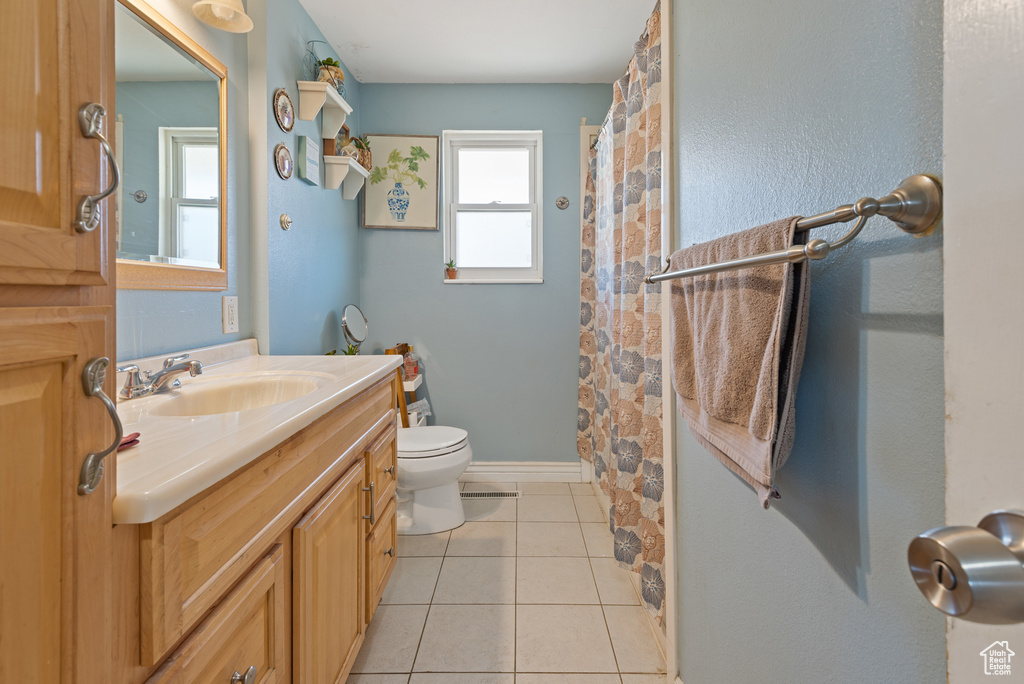 Full bath featuring baseboards, a shower with shower curtain, toilet, tile patterned flooring, and vanity