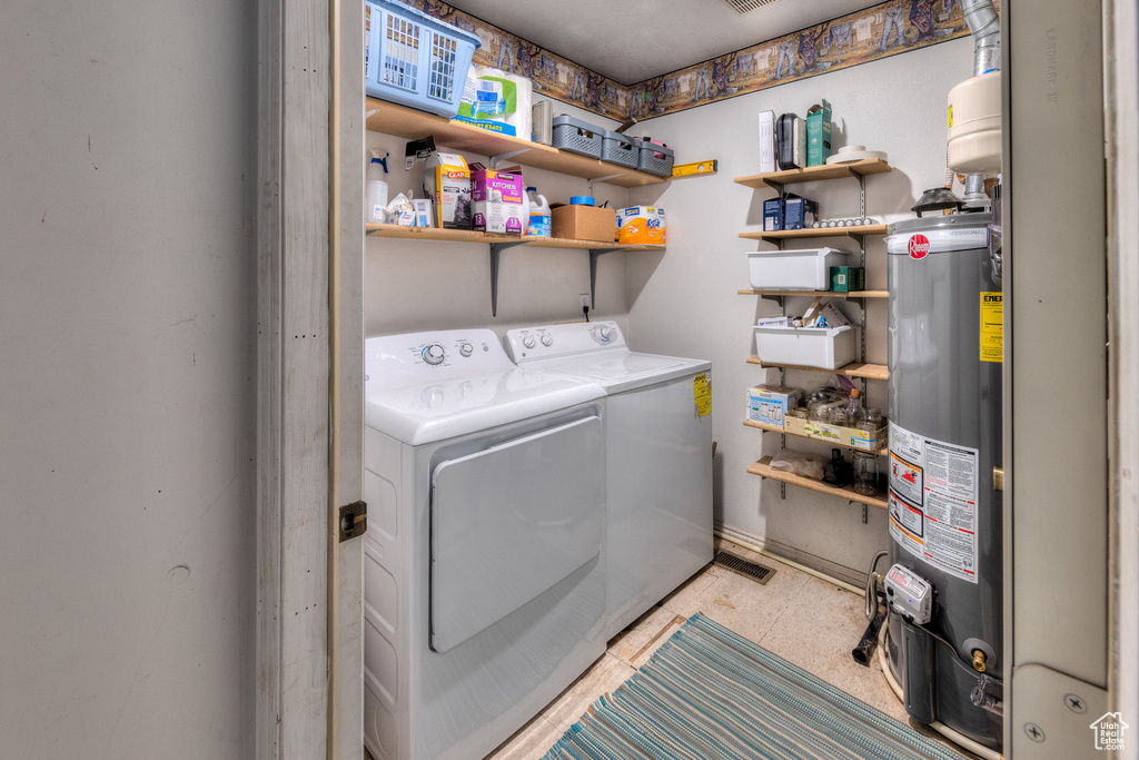 Washroom featuring water heater, washer and clothes dryer, and baseboards