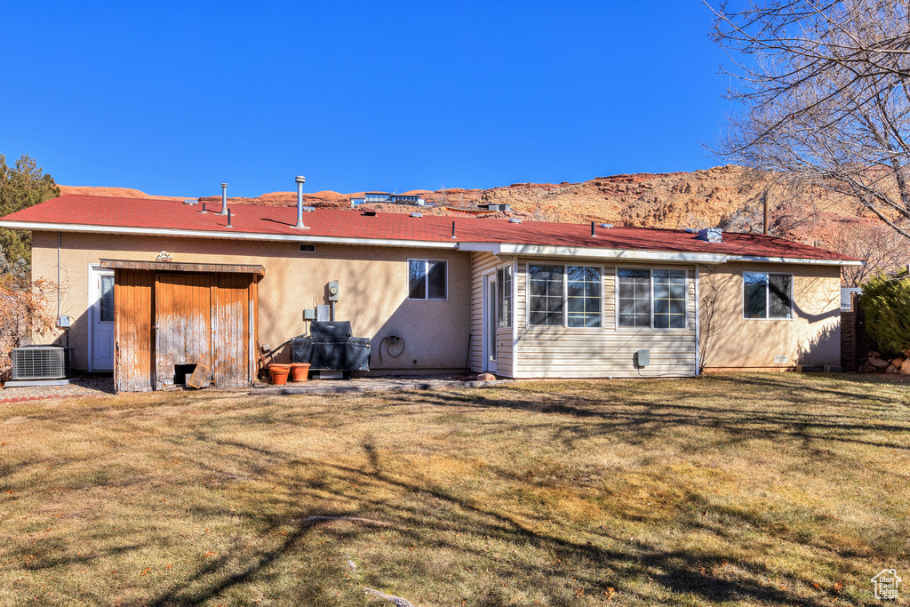 Back of property featuring central AC and a lawn