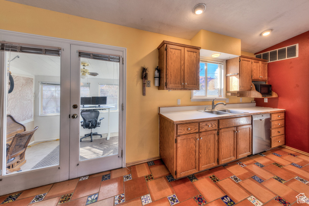 Kitchen with stainless steel dishwasher, a sink, brown cabinetry, light countertops, and black microwave