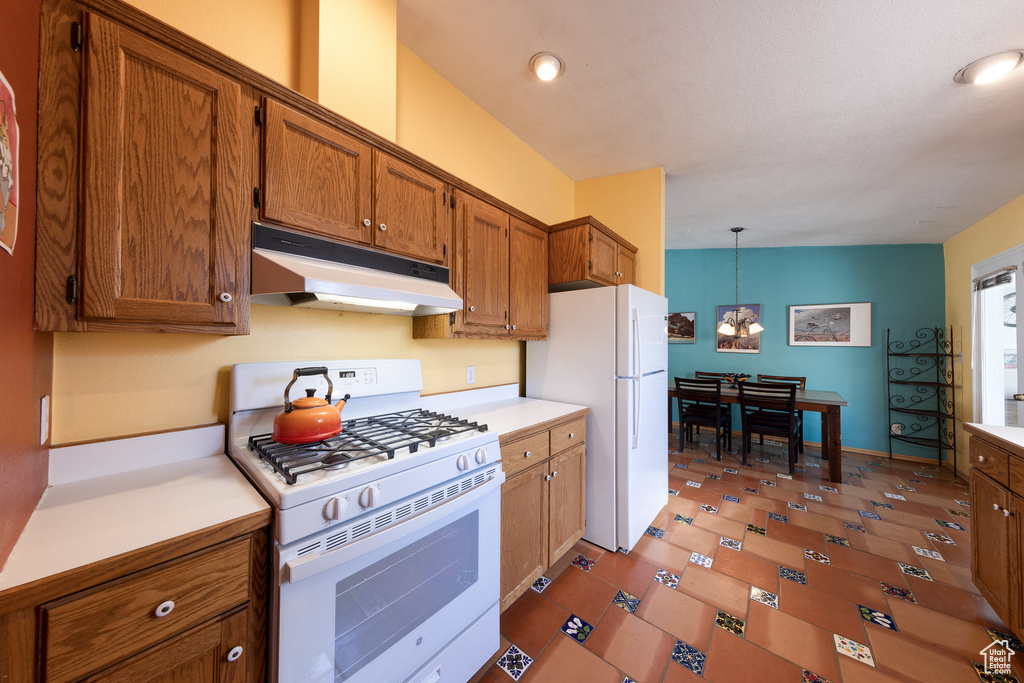 Kitchen featuring white appliances, under cabinet range hood, brown cabinets, light countertops, and recessed lighting