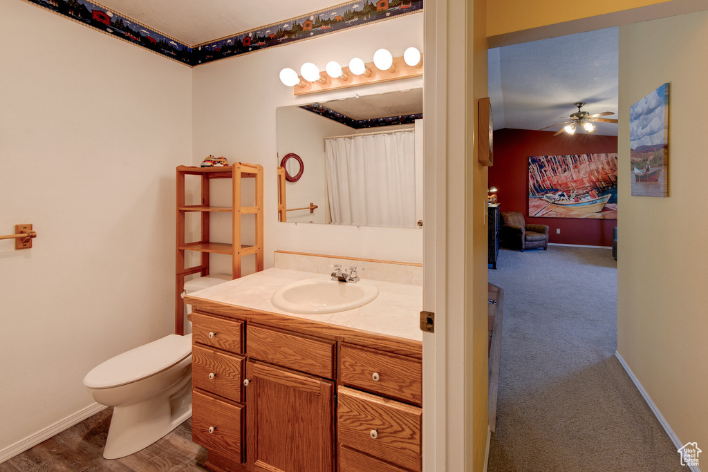 Bathroom featuring vanity, toilet, baseboards, and ceiling fan
