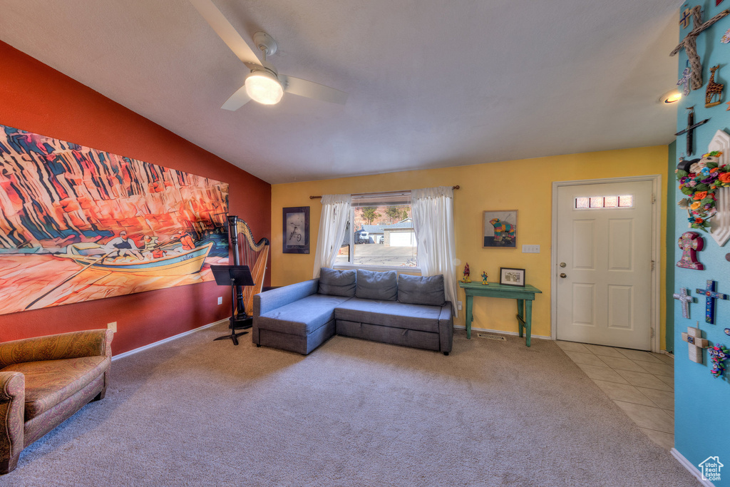 Carpeted living room with ceiling fan, vaulted ceiling, baseboards, and tile patterned floors