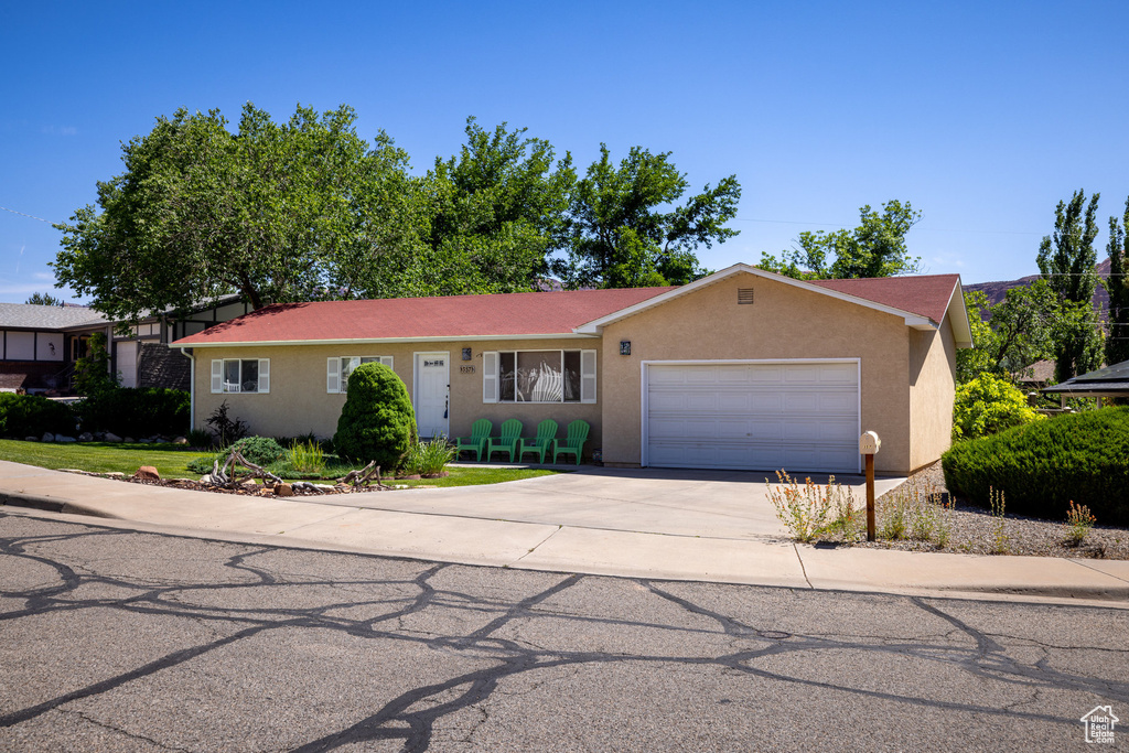 Ranch-style home featuring an attached garage, concrete driveway, and stucco siding