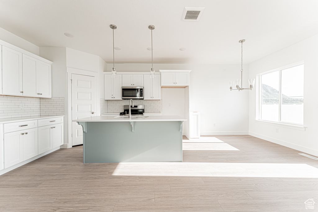 Kitchen with appliances with stainless steel finishes, backsplash, and white cabinets