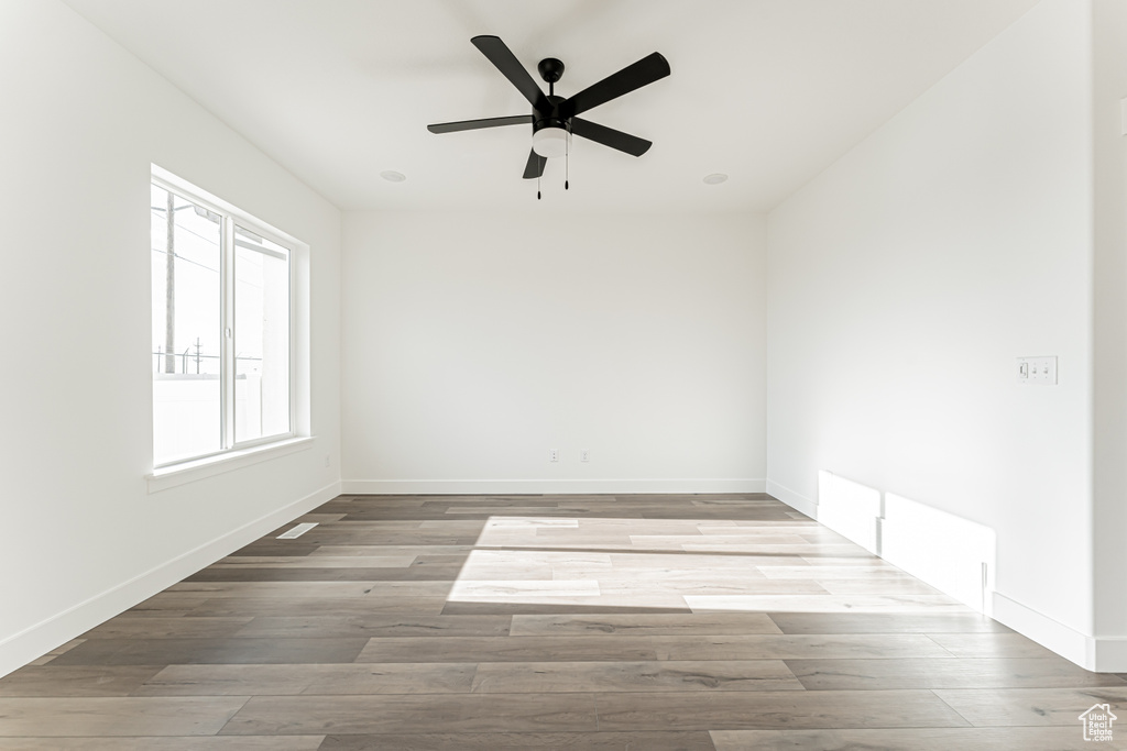 Spare room with wood finished floors, baseboards, and a ceiling fan