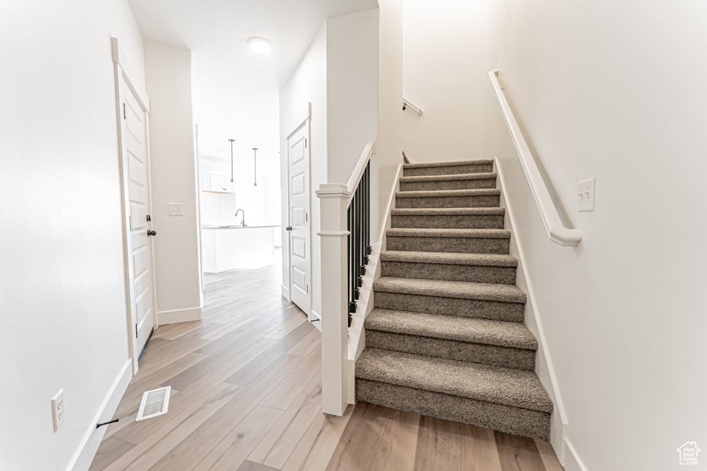 Stairs with wood finished floors and baseboards