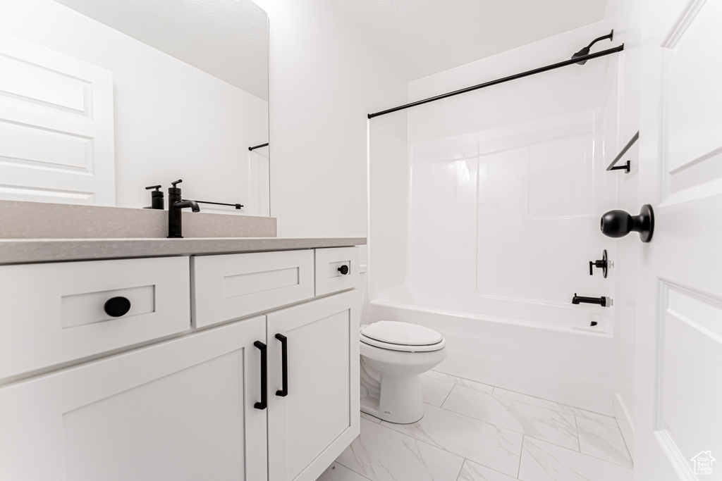 Full bathroom with vanity, toilet, marble look tiles, and shower / washtub combination