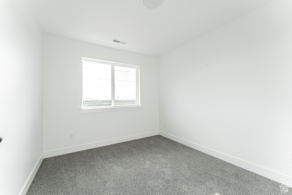 Spare room featuring dark carpet and baseboards