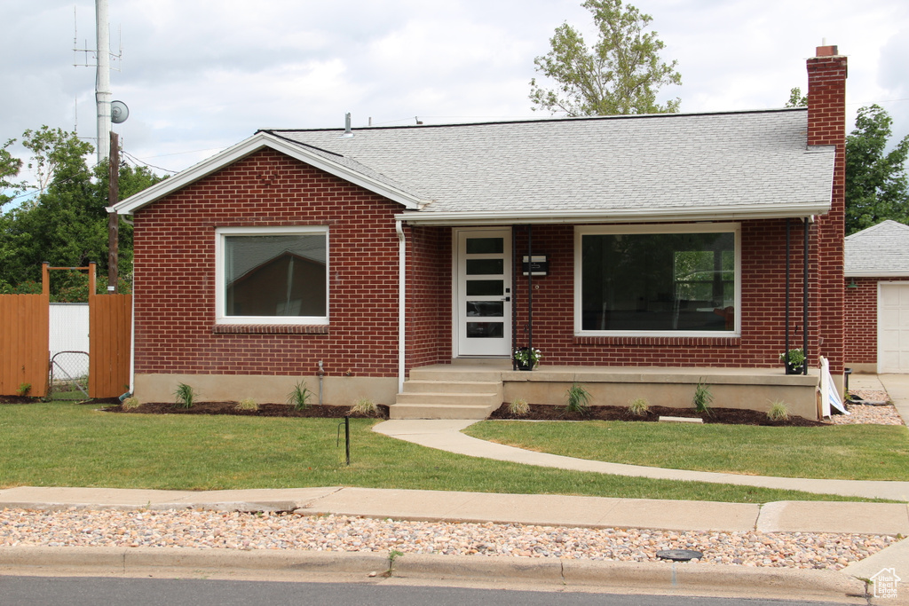 View of front facade with a chimney, brick siding, and roof with shingles