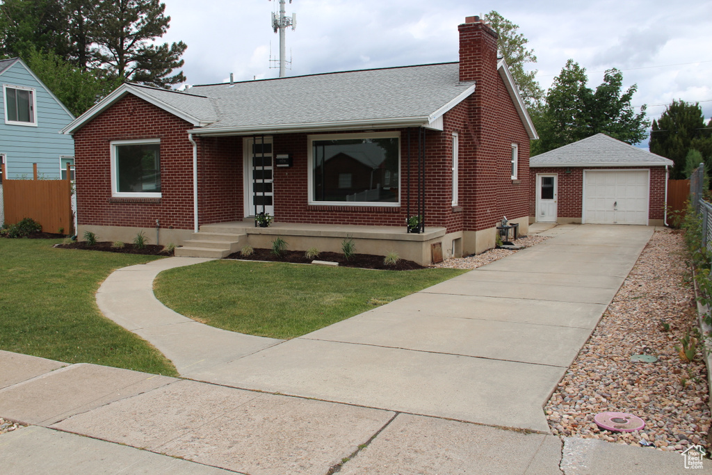 View of front facade with brick siding, an outdoor structure, covered porch, a chimney, and driveway