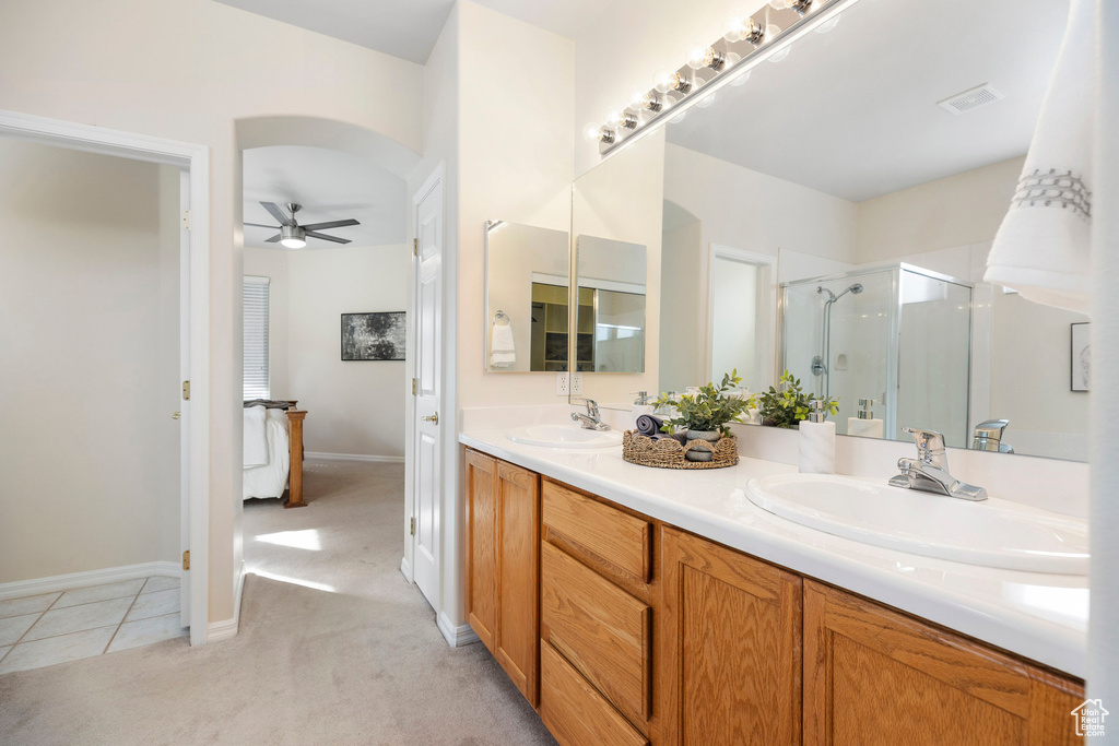 Full bath with a ceiling fan, a shower stall, double vanity, tile patterned floors, and baseboards