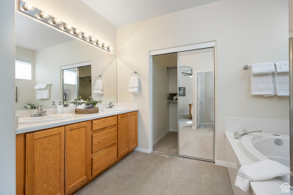 Full bath featuring a garden tub, double vanity, baseboards, and carpet flooring