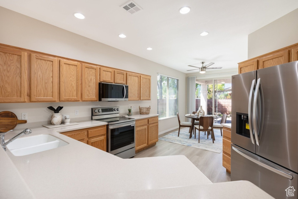 Kitchen with appliances with stainless steel finishes, a sink, light countertops, light wood-style floors, and recessed lighting