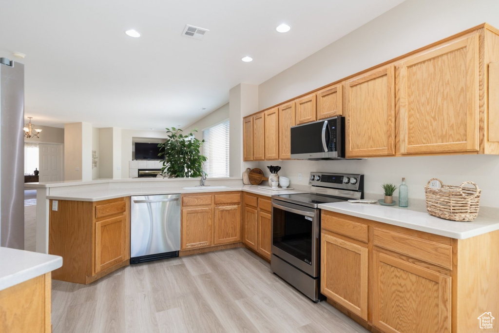 Kitchen featuring appliances with stainless steel finishes, a sink, a peninsula, a chandelier, and open floor plan