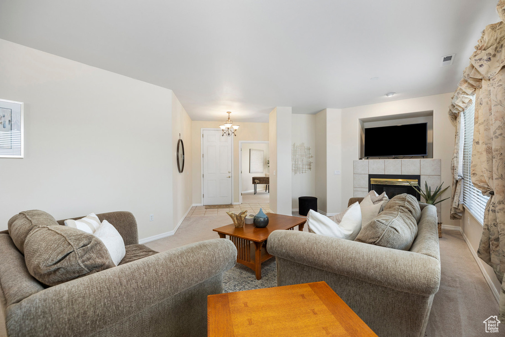 Living area with light colored carpet, a fireplace, a chandelier, and baseboards