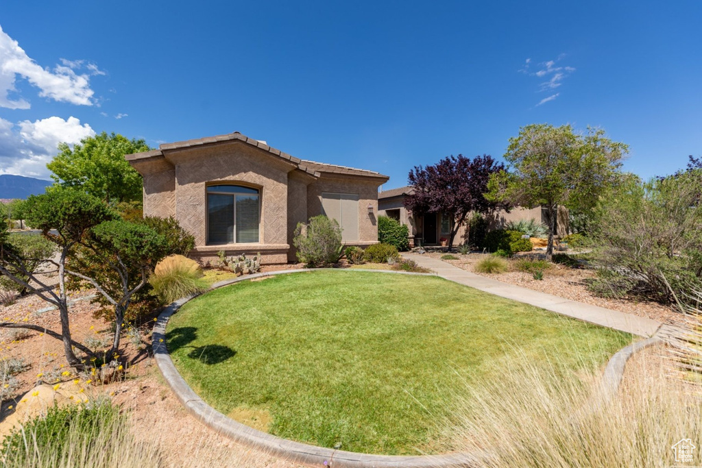 View of front of home with stucco siding, a front lawn, and a tiled roof