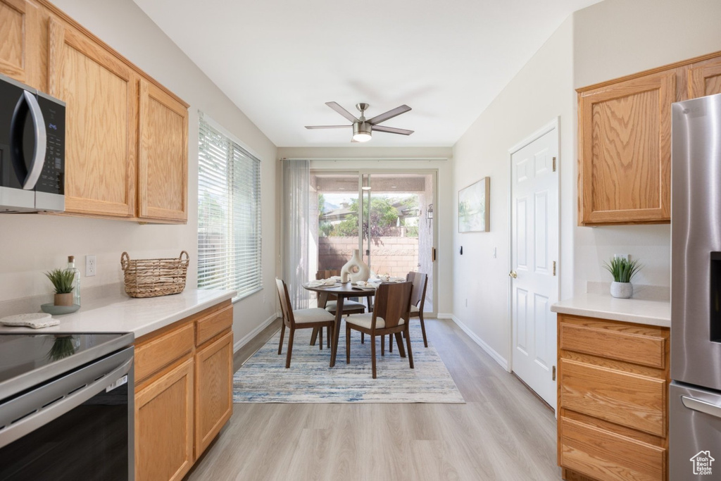 Kitchen with appliances with stainless steel finishes, light wood-style flooring, a ceiling fan, light countertops, and light brown cabinets