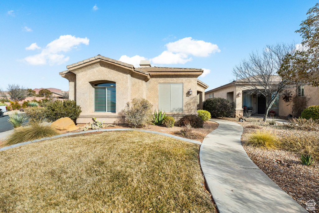 View of front facade with stucco siding, a front lawn, and a tiled roof