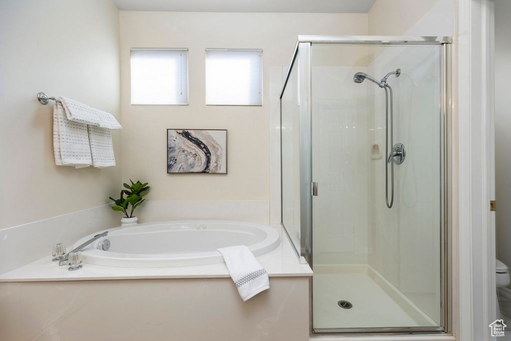 Full bathroom featuring a shower stall, a garden tub, and toilet