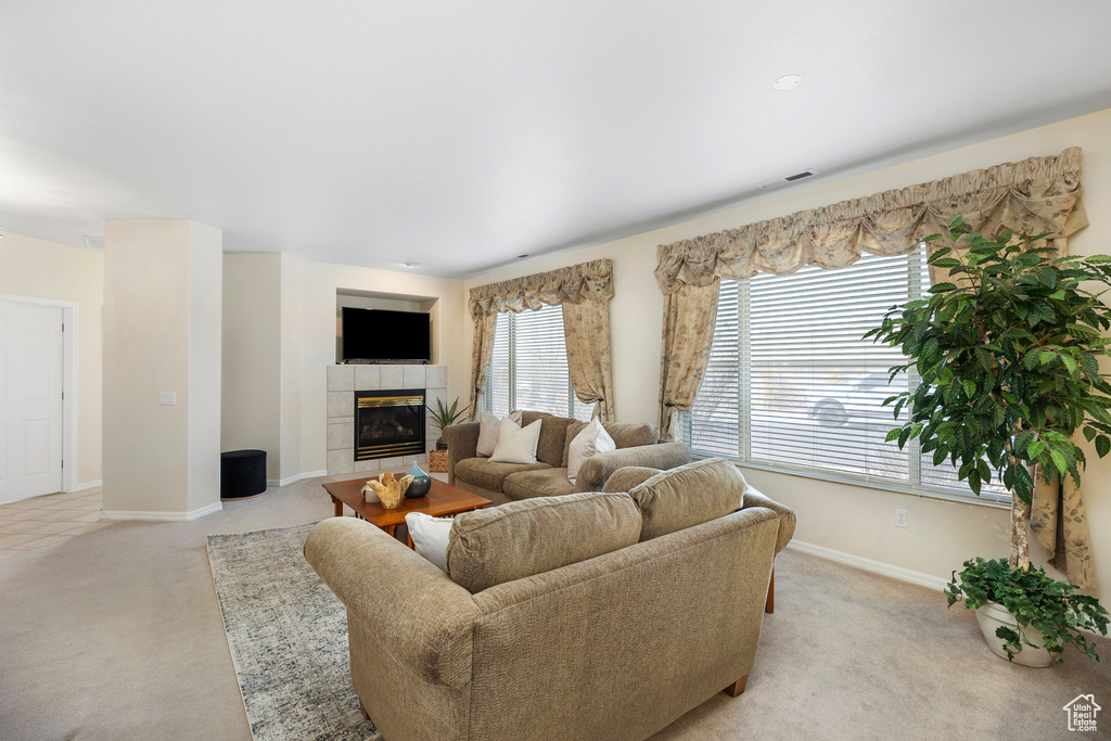 Living area with light carpet, baseboards, and a tile fireplace