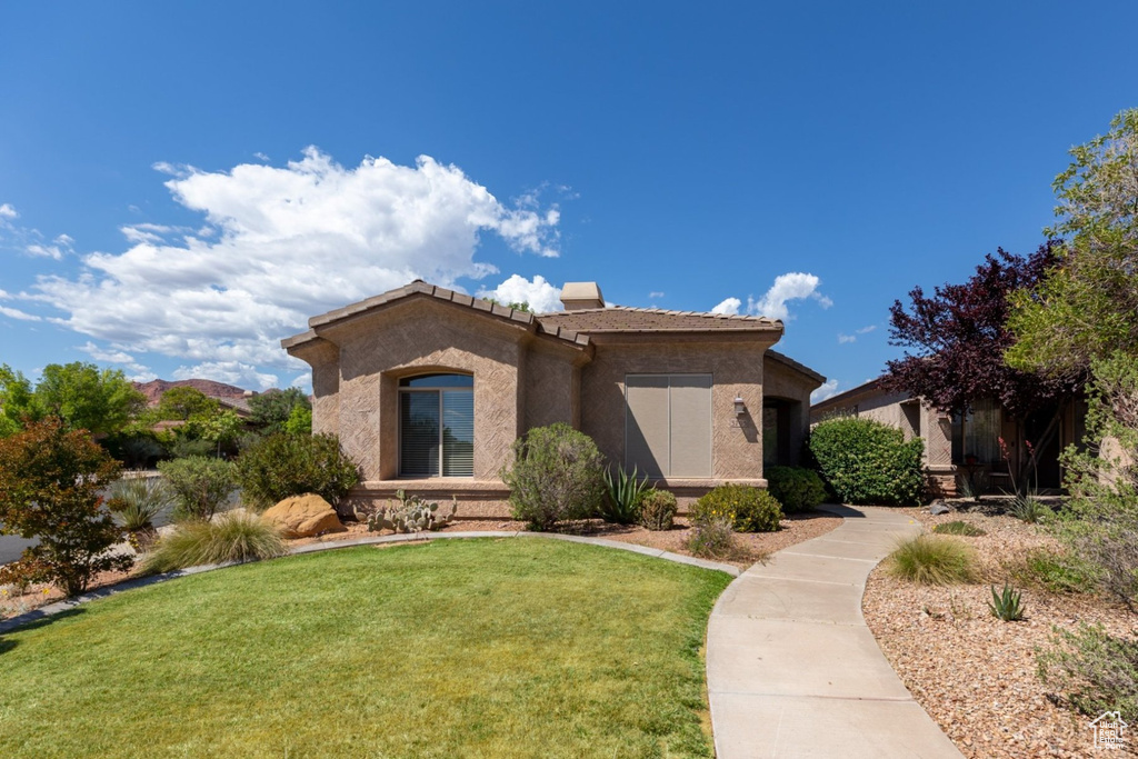 View of front of home with a front lawn, a tiled roof, and stucco siding
