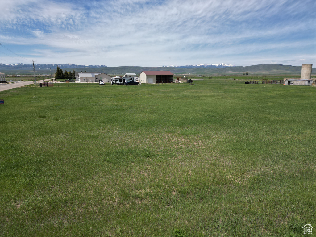 View of grassy yard with a mountain view, a view of rural / pastoral area, and an outbuilding