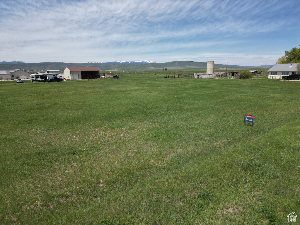 View of grassy yard with a mountain view, an outbuilding, a pole building, and a detached garage