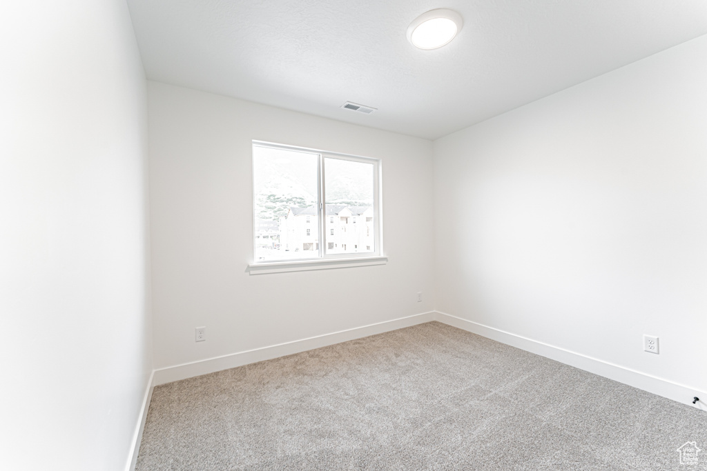 Spare room featuring carpet flooring and baseboards