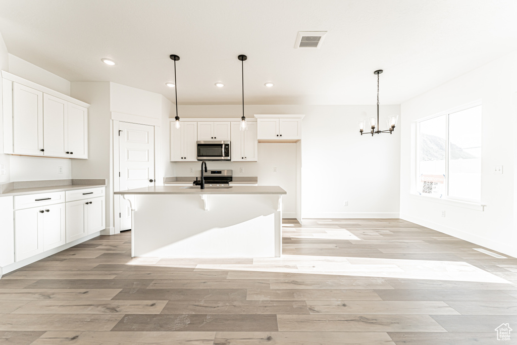 Kitchen featuring stainless steel appliances, recessed lighting, white cabinets, light wood-style floors, and a chandelier