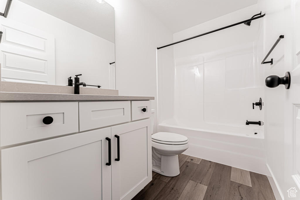 Bathroom featuring vanity, shower / bathtub combination, and wood finished floors