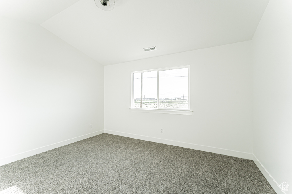 Unfurnished room with lofted ceiling, dark colored carpet, and baseboards