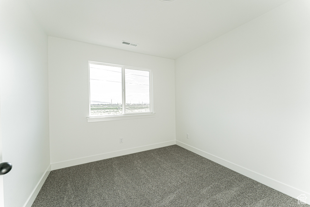 Spare room featuring dark carpet and baseboards
