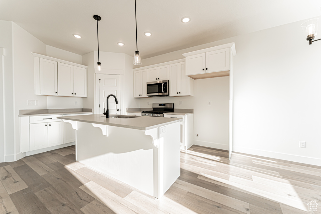 Kitchen with appliances with stainless steel finishes, a sink, recessed lighting, light wood-style flooring, and white cabinets