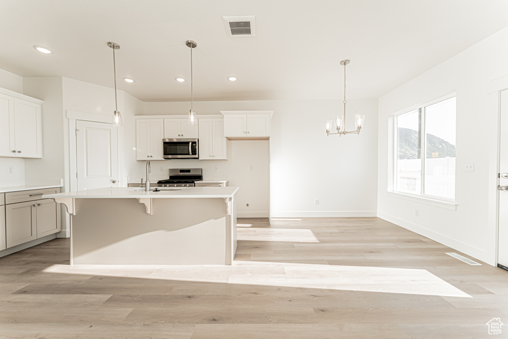 Kitchen featuring appliances with stainless steel finishes, a chandelier, recessed lighting, light wood-style floors, and light countertops