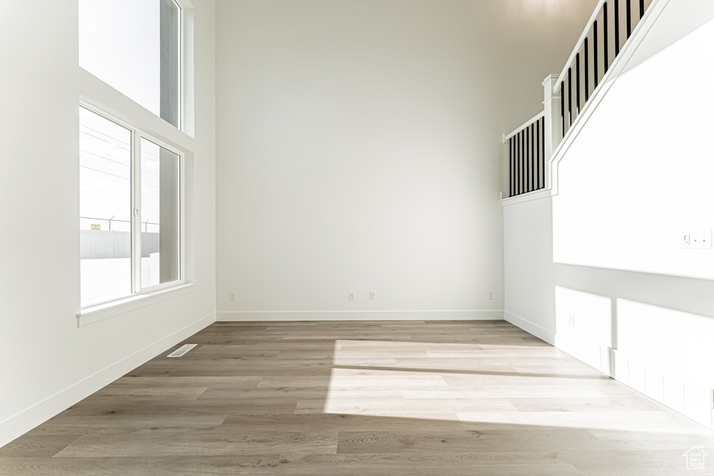 Empty room featuring wood finished floors, baseboards, and a towering ceiling