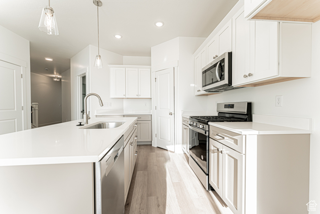 Kitchen featuring stainless steel appliances, a sink, light wood finished floors, recessed lighting, and light countertops