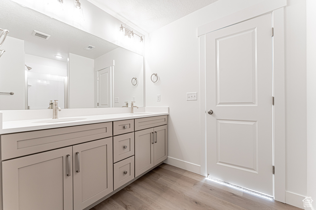 Bathroom featuring double vanity, wood finished floors, and baseboards