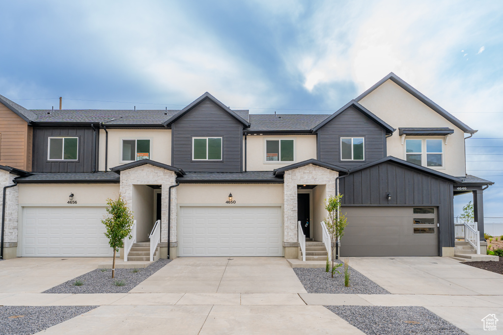 View of front of home featuring a garage, driveway, stone siding, and a shingled roof