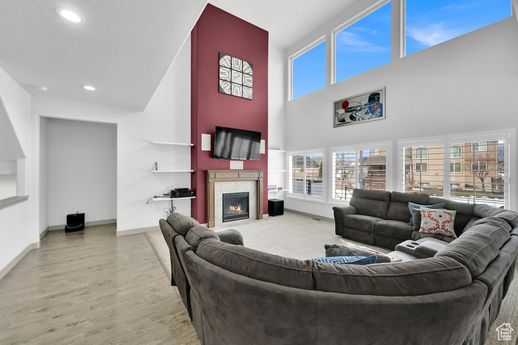 Living room with light hardwood / wood-style flooring, a textured ceiling, and a high ceiling